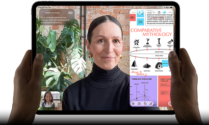 iPad Pro, front exterior, landscape orientation, space black color, rounded corners, black display bezel, hands holding left and right sides, display showing a FaceTime conversation being live translated, and an educational app showing a presentation of "Comparative Mythology" with text, diagrams, and handwritten notes