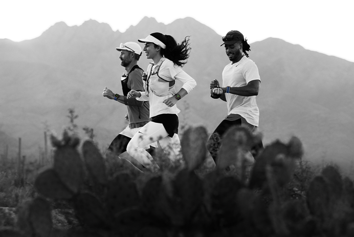 Three people running in a mountainous area, all wearing Apple Watch Ultra 3